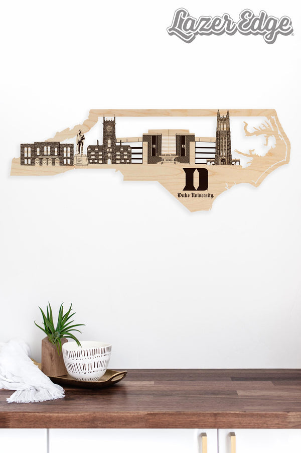 a wooden cutout of a city skyline with a bowl of fruit and a plant on a wooden surface.